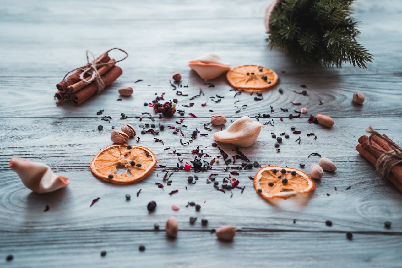 A flatlay of dried citrus slices, cinnamon sticks, and spices on a wooden table, creating a festive feel.